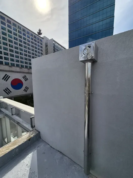 옥상 가장자리에서 본 동일 배수구와 스테인리스 배관, 정리된 벽면